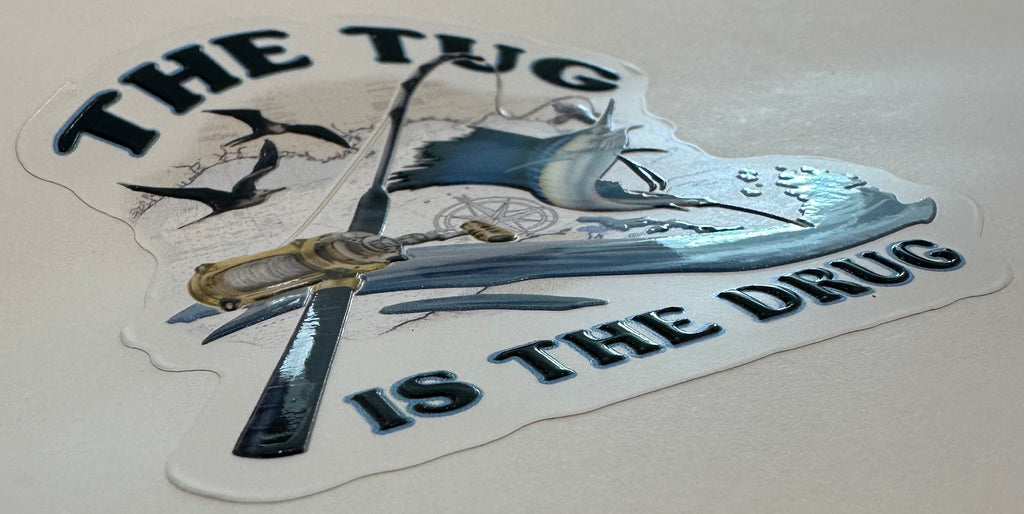 The Tug Is The Drug sailfish embossed fishing sticker with rod, reel, waves, and offshore artwork.